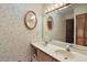 Bathroom with double sinks, large mirror, vanity lighting, and floral wallpaper at 10290 Buck Rd, Orlando, FL 32817