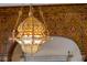 Ornate, gold color chandelier hangs from the ceiling with patterned gold trim at 4852 S Peninsula Dr, Ponce Inlet, FL 32127