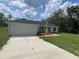 Inviting single-story home featuring a long driveway, attached garage, and well-manicured front lawn at 75 Guava Place Dr, Ocklawaha, FL 32179