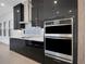 Modern kitchen with black cabinets, stainless steel appliances, and quartz countertops at 3016 Kensington Ave, Davenport, FL 33837