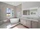 Modern bathroom featuring a soaking tub, marble tiled walls and floor, and backlit mirror at 260 Deer Isle Dr, Winter Garden, FL 34787
