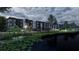 Exterior view of modern apartments overlooking a pond, framed by lush greenery and a security fence at 4424 S Texas Ave, Orlando, FL 32839