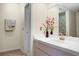Bathroom featuring a white tiled countertop and sink, a gold faucet, and a mirror with red orchid accents at 6254 Masters Blvd # D106, Orlando, FL 32819