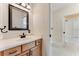 Bathroom vanity featuring wood cabinets, light marble countertops, and a dark framed mirror above the sink at 10843 Lakeshore Dr, Clermont, FL 34711