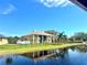Stately two-story home with a manicured lawn, black fence, and waterfront views at 10843 Lakeshore Dr, Clermont, FL 34711