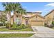 Two-story house with tan exterior, palm trees, and a two-car garage at 6078 Broad Oak Dr, Davenport, FL 33837