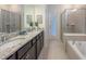 Luxurious bathroom featuring double sinks, a walk-in shower, and a soaking tub at 4189 Lana Ave, Davenport, FL 33897