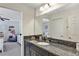 Bathroom featuring dark cabinets, granite countertop, and large mirror showcasing the attached bedroom at 9149 Outlook Rock Trl, Windermere, FL 34786