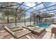 Screened-in pool area with a pool, spa, patio furniture, and trees in the background at 9149 Outlook Rock Trl, Windermere, FL 34786