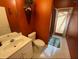 Bathroom with orange walls, and white toilet, vanity and sink with view to exterior door at 466 Pepin Dr, Orlando, FL 32825