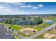 Community aerial view showcasing green spaces, sidewalks, a playground, and a lake on a sunny day at 14038 Scarlet Aster Aly, Winter Garden, FL 34787