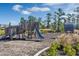 A playground area with wooden structures, a slide, and a mulch ground covering surrounded by landscaping and trees at 14038 Scarlet Aster Aly, Winter Garden, FL 34787