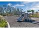 A playground area features wooden structures, a slide, and a mulch ground covering surrounded by landscaping and trees at 14038 Scarlet Aster Aly, Winter Garden, FL 34787