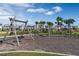 A playground with swings in a community area featuring landscaping, palm trees, and residential homes at 14046 Scarlet Aster Aly, Winter Garden, FL 34787