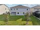 Rear exterior showcasing a covered patio and a well-kept lawn, framed by lush trees and the home's gray facade at 4949 Olivia Ct, St Cloud, FL 34772