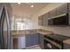 Modern kitchen featuring stainless steel appliances, granite counters, and sleek gray cabinetry at 4712 Hemingway House St, Kissimmee, FL 34746