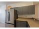 Well-lit kitchen showcasing a stainless steel refrigerator, gray cabinets, and neutral countertops at 4712 Hemingway House St, Kissimmee, FL 34746