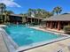 Large community pool with plenty of deck chairs surrounded by mature palms at 750 E Michigan St # 163, Orlando, FL 32806