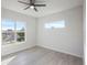 Spacious bedroom featuring two windows, a ceiling fan, and light grey wood-look flooring at 208 Snowy Orchid Way, Lake Alfred, FL 33850