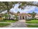 Beautiful two-story home with a tile roof, lush landscaping, and a brick paved driveway at 6130 Blakeford Dr, Windermere, FL 34786
