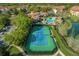 Aerial view of a community tennis court, swimming pool, clubhouse, parking, and surrounding lush greenery at 637 Pavia Loop, Lake Mary, FL 32746