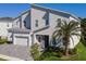 Charming two-story home boasts an attached garage, stone accents, a palm tree, and a manicured lawn at 1758 Oak Blossom Dr, Davenport, FL 33837