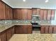 Well-lit kitchen featuring granite countertops, tiled backsplash, stainless steel appliances, and stylish brown cabinetry at 4904 Blanche Ct, Saint Cloud, FL 34772