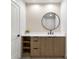 Modern bathroom vanity with wood cabinets and a large round mirror at 6000 Tarawood Dr, Orlando, FL 32819