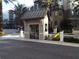 A gray guardhouse with a dark metal roof on an asphalt road with lush landscaping and other buildings in the background at 14501 Grove Resort Ave # 1105, Winter Garden, FL 34787