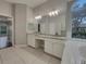 Bathroom featuring double vanities with granite countertops, and large mirror, with a soaking tub at 148 Blue Stone Cir, Winter Garden, FL 34787