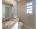 Well-lit bathroom featuring a granite countertop vanity, toilet, and window at 759 Little Wekiva Cir, Altamonte Springs, FL 32714