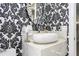 Chic powder room boasts a floating vanity and unique wallpaper at 8042 Ludington Cir, Orlando, FL 32836