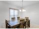 Cozy dining area with a wooden dining table, chairs, chandelier, and a window providing natural light at 687 Campo Ln, Davenport, FL 33837