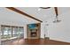 Cozy living room with a stone fireplace, wood beam, and glass sliding doors to outdoor patio at 128 W Juliana Way, Auburndale, FL 33823