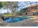Gorgeous screened pool and patio area with a waterfall feature, spa, and beautiful landscaping at 128 W Juliana Way, Auburndale, FL 33823