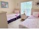Charming bedroom featuring two twin beds, carpet, and a sunny window view to the outdoors at 2555 Oneida Loop, Kissimmee, FL 34747