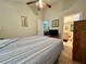 Well-lit bedroom featuring queen bed, ceiling fan, dresser, and access to a private en-suite bathroom at 2555 Oneida Loop, Kissimmee, FL 34747