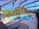 Bask in this inviting screened-in pool and spa with lounge chairs and lush greenery beyond at 2555 Oneida Loop, Kissimmee, FL 34747