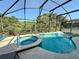Private backyard pool and spa area with tropical landscaping, covered by screened enclosure at 2555 Oneida Loop, Kissimmee, FL 34747