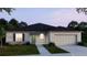 House exterior at dusk showcasing gray siding, a two-car garage, and front landscaping at 2235 Elegant Manor Cir, Edgewater, FL 32141