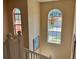 Staircase with a view of the entry, featuring two arched windows that allow natural light to illuminate the interior at 5450 Watervista Dr, Orlando, FL 32821