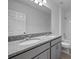 Bright bathroom featuring double sinks with granite countertop, gray cabinetry and a shower-tub combo at 4054 Serene Water Ave, Eustis, FL 32736