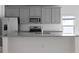 Modern kitchen with gray cabinets, granite countertops, stainless steel appliances, and stylish tile backsplash at 4054 Serene Water Ave, Eustis, FL 32736