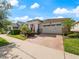 Charming single-Gathering home boasting a brick driveway, a two-car garage, and lush, colorful landscaping at 4904 W Fountainwood Dr, St Cloud, FL 34772