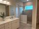 Modern bathroom featuring a walk-in shower, white vanity, and a large, bright mirror at 3962 Kennebunk Loop, Mount Dora, FL 32757