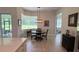 Sunlit dining area featuring wood floors and a modern chandelier, adjacent to the kitchen at 3962 Kennebunk Loop, Mount Dora, FL 32757