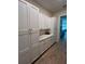 Hallway with long, custom, white cabinets with stone countertop and wood floor extending into background at 3962 Kennebunk Loop, Mount Dora, FL 32757