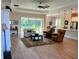 Open-concept living room with large windows, wood-look flooring and seamless access to the dining area at 3962 Kennebunk Loop, Mount Dora, FL 32757