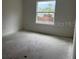 Simple bedroom featuring a large window, light-colored walls, and unfinished floors at 1445 General Mac Arthur Ave, Daytona Beach, FL 32114