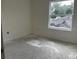 Simple bedroom featuring a large window, light-colored walls, and unfinished floors at 1445 General Mac Arthur Ave, Daytona Beach, FL 32114